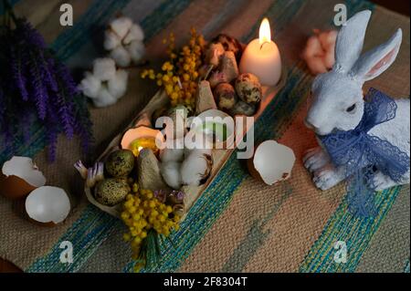 Easter decor in an egg box with candles, hare and dried flower Stock Photo