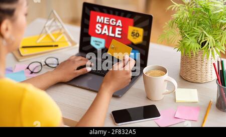 Young woman shopping on Internet, using laptop in office, cropped Stock Photo