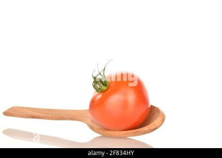 One ripe, bright red, organic, tasty cocktail tomato with a wooden spoon, close-up, on a white background. Stock Photo