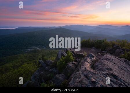 A hiker enjoys a colorful Summer sunrise from Mary's Rock in Shenandoah National Park. Stock Photo