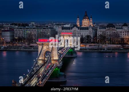 Budapest, Hungary - The world famous illuminated Szechenyi Chain Bridge (Lanchid) by night, lit up with national red, white and green colors, celebrat Stock Photo