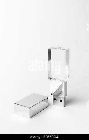 Glass USB stick with a metal cover on a gray background. Copy space. Vertical close-up photo. Stock Photo