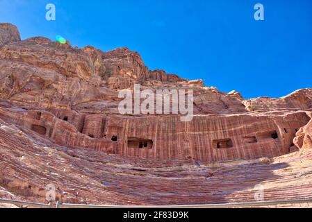 The caves along the back of the theater most likely come from older tombs that were removed in order to carve the theater seats  Taken @Petra, Jordan Stock Photo