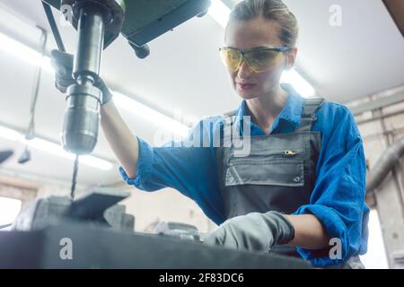 Woman worker in metal workshop using pedestal drill Stock Photo