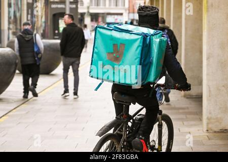 Cardiff, Wales - April 2021: Person riding a bicycle in Cardiff city centre making a delivery for Deliveroo. Stock Photo