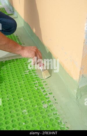 worker applies waterproofing with a small brush Stock Photo