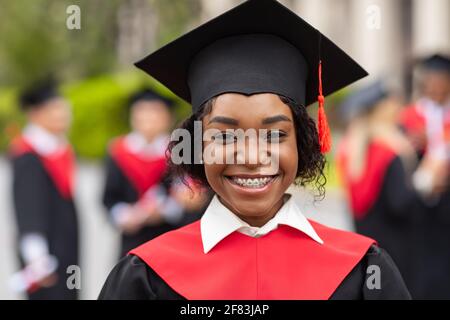 Closeup portrait of happy black lady student wearing graduating costume Stock Photo