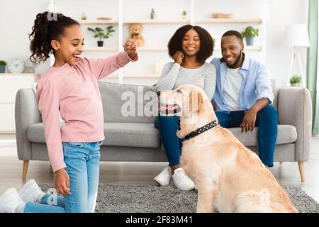Black girl giving a treat to her obedient dog Stock Photo