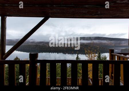 View of a lake from a balcony with a wooden fence and clouds Stock Photo