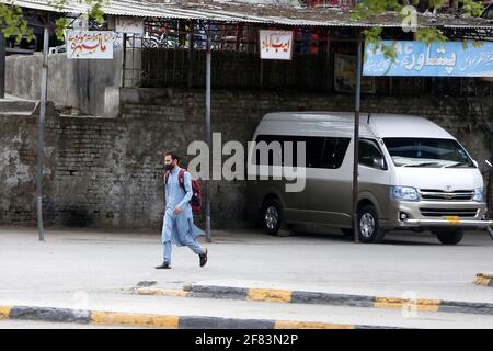 Islamabad. 11th Apr, 2021. Photo taken on April 11, 2021 shows a man walking back from a closed bus station in Islamabad, Pakistan. To counter the deadly third wave of COVID-19, Pakistan has recently taken several measures by banning all kinds of both indoor and outdoor mass gatherings, closing educational institutions in some areas of the country and suspending inter-provincial transport two days a week from April 10 to 25. Credit: Ahmad Kamal/Xinhua/Alamy Live News Stock Photo