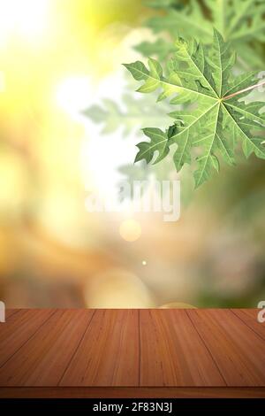 Empty wood table and defocused bokeh blur background with papaya leaf. Stock Photo