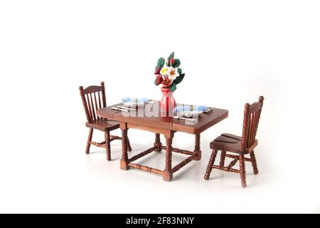 dollhouse interior - served dining table with a bowl with flowers isolated on white background. Image contains copy space Stock Photo