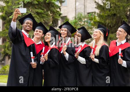 Cheerful multiracial group of students taking selfie on smartphone Stock Photo