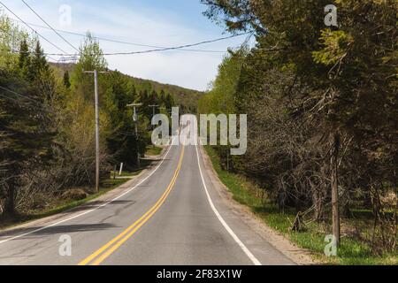 small one lane road in summer in the countryside that goes uphill a little Stock Photo