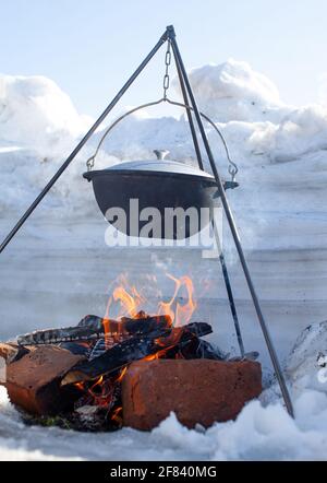 https://l450v.alamy.com/450v/2f840mg/over-the-fire-hangs-a-pot-in-which-to-cook-food-on-a-hook-on-a-tripod-steam-comes-out-of-the-pan-winter-camping-outdoor-cooking-2f840mg.jpg