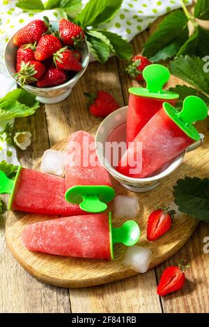 Summer dessert. Homemade strawberry frozen fruit juice, Strawberry Ice cream or strawberry popsicles on a rustic table. Stock Photo