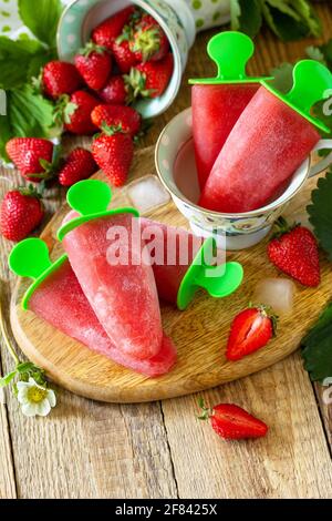 Summer dessert. Homemade strawberry frozen fruit juice, Strawberry Ice cream or strawberry popsicles on a rustic table. Copy space. Stock Photo