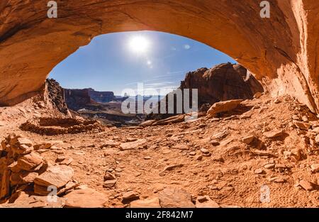 view of a valley from under an arch made of red rock by natural erosion Stock Photo