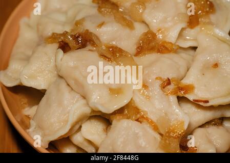 Dumplings in bowl with fried onions. Dumplings, filled with mashed potato served with fried onion Stock Photo