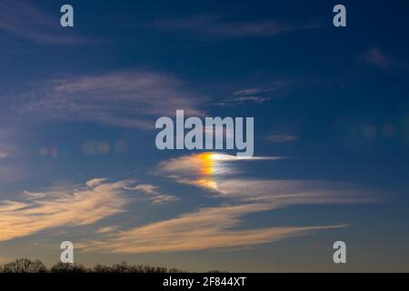 view of the sky with bright light on a cloud creating a rainbow Stock Photo
