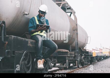 African male engineer control a the train on railway with talking by radio communication or walkie talkie with using tablet Stock Photo