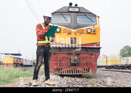 African man engineer looking report of Train Timetables for control a the train on railway Stock Photo