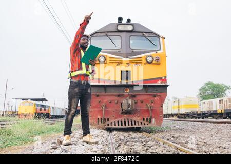 African man engineer looking report of Train Timetables for control a the train on railway Stock Photo