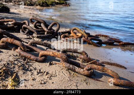 Rusty old chain on sandy beach Stock Photo