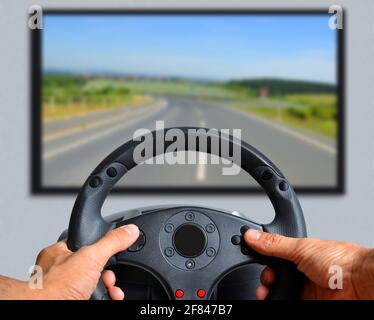Hands holding gaming steering wheel.  The gamer is playing a car race. Stock Photo