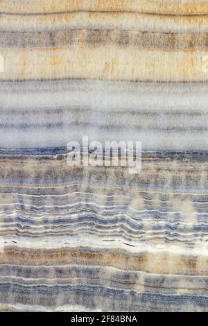 Beige marble texture with wavy gray, brown and blue horizontal stripes. Polished surface. Vertical image. Stock Photo