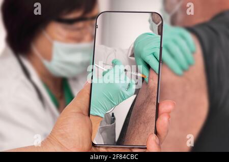 Taking a picture of man getting vaccinated Stock Photo