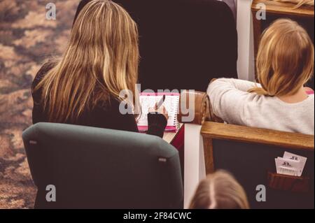 A female making notes during a lecture in a hall Stock Photo