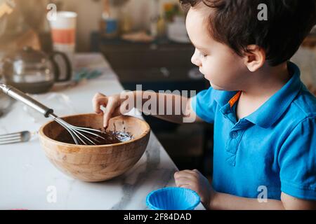 A little boy licks a whisk with chocolate dough Stock Photo