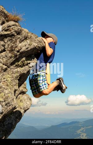 The boy is engaged in mountaineering, a child climbing a rocky mountain, a brave boy.2020 Stock Photo