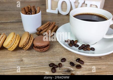 coffee break with cup of espresso and colorful macarons of chocolate, hazelnut, vanilla, salted butter. on the table cinnamon Stock Photo