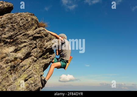 The boy is engaged in mountaineering, a child climbing a rocky mountain, a brave boy.2020 Stock Photo