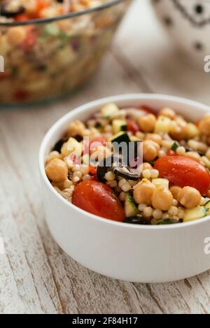Home made Mediterranean couscous salad with bell pepper, zucchini, tomatoes, chickpeas, olive and vegan feta.