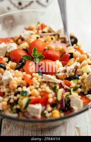 Home made Mediterranean couscous salad with bell pepper, zucchini, tomatoes, chickpeas, olive and vegan feta.