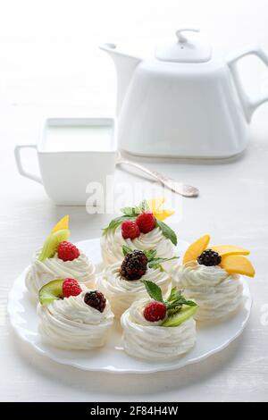Homemade mini pavlova cakes with whipped cream and fresh berries on light  background Stock Photo