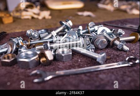 Metal nuts bolts and a wrench lie on the work table of the assembler Stock Photo