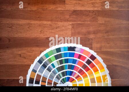 an open color swatch with all the different colors folded out on a wooden surface, cherry colored wood texture, horizontal Stock Photo
