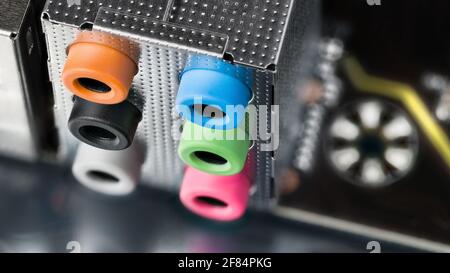 Colored audio connectors for sound on computer mainboard detail. Close-up of modern microphone or headphones output and input on a black circuit board. Stock Photo