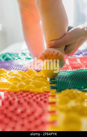 Mom gives the baby a foot massage with massage balls. Close-up Stock Photo