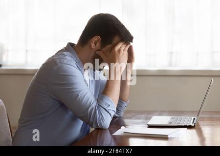 Unhappy man feel distressed working on computer Stock Photo