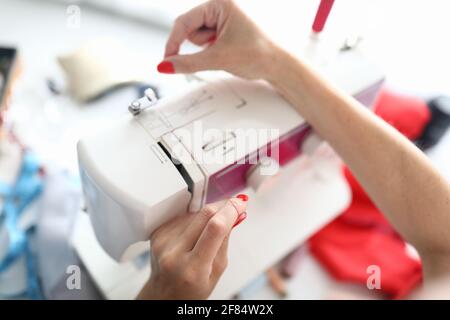 Top view of red thread on white sewing machine. Professional device for sew clothes Stock Photo