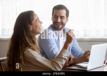 Happy millennial couple have fun using laptop at home Stock Photo