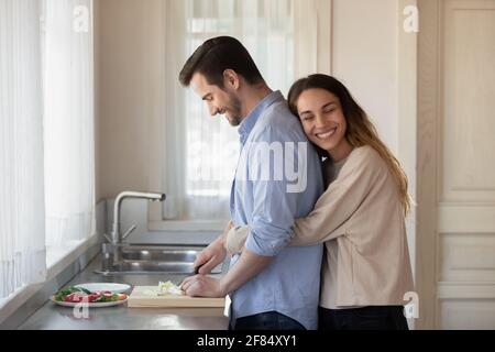 Happy couple renters cook together in kitchen Stock Photo