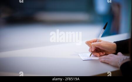 Close up view of womans hand writing in notebook. Girl making notes with pen on white table. Copy space Stock Photo