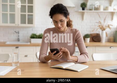 Young hispanic woman freelancer set up business meeting using cell Stock Photo