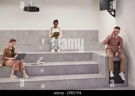 Minimal wide angle shot of diverse group of students relaxing in modern school lounge during break, copy space Stock Photo